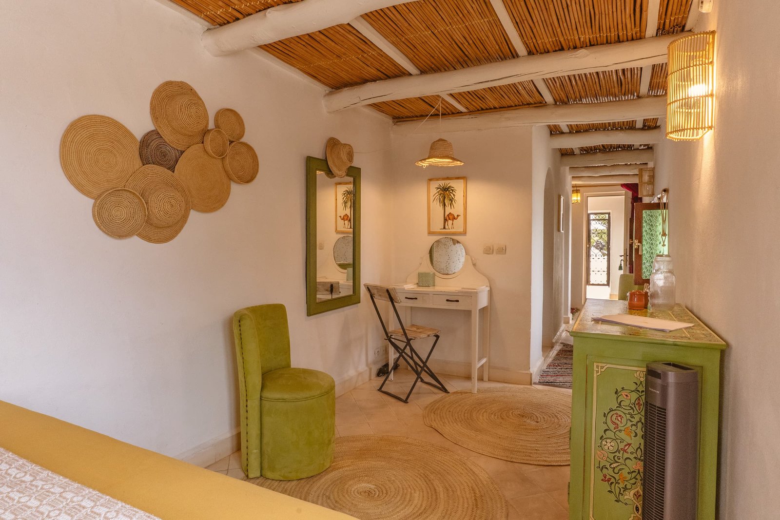 La chambre Émeraude, ses paniers au mur, son fauteuil vert et son plafond de roseaux