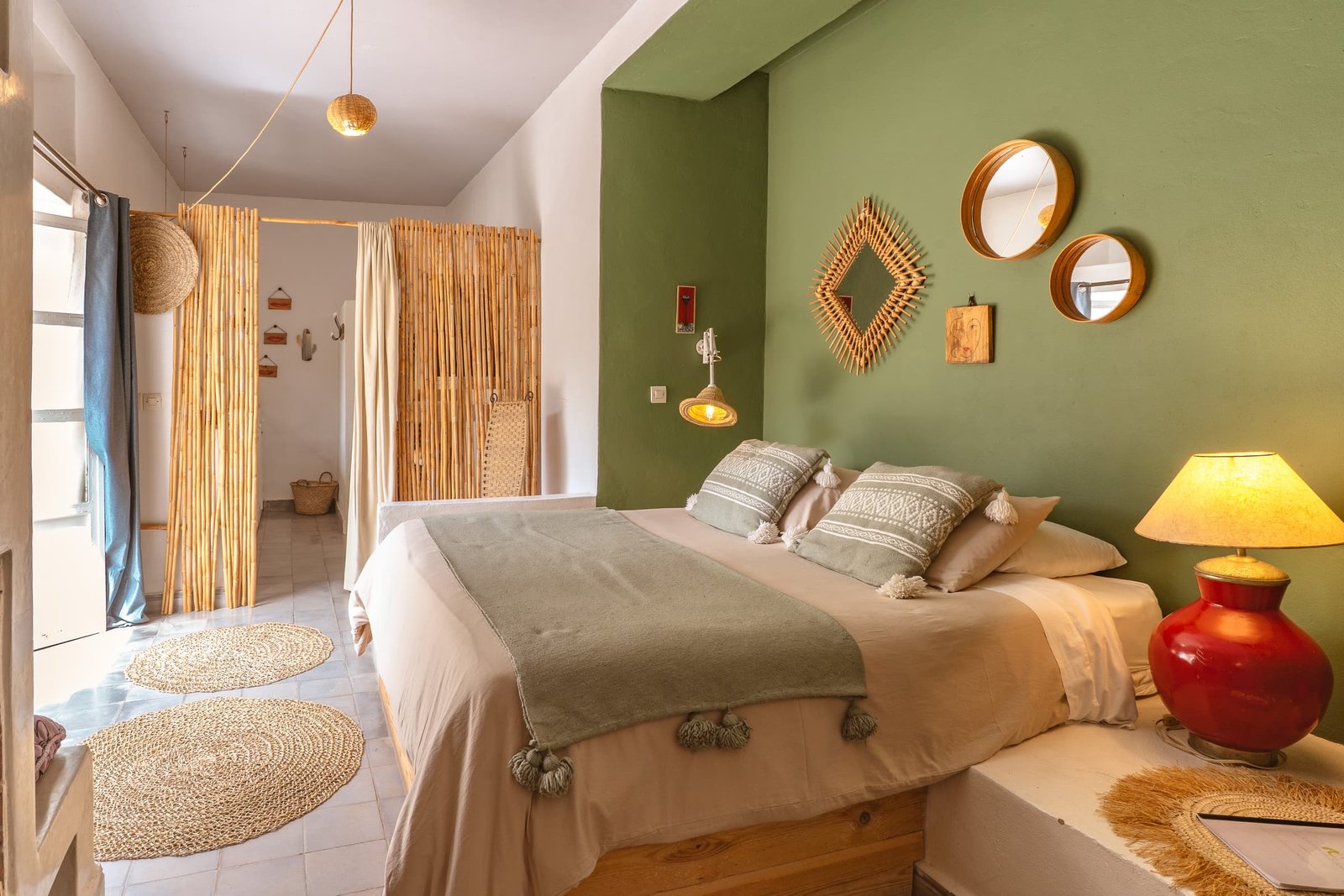 La première chambre de la suite Bambou, mur vert, miroirs ronds et paravent de bambou