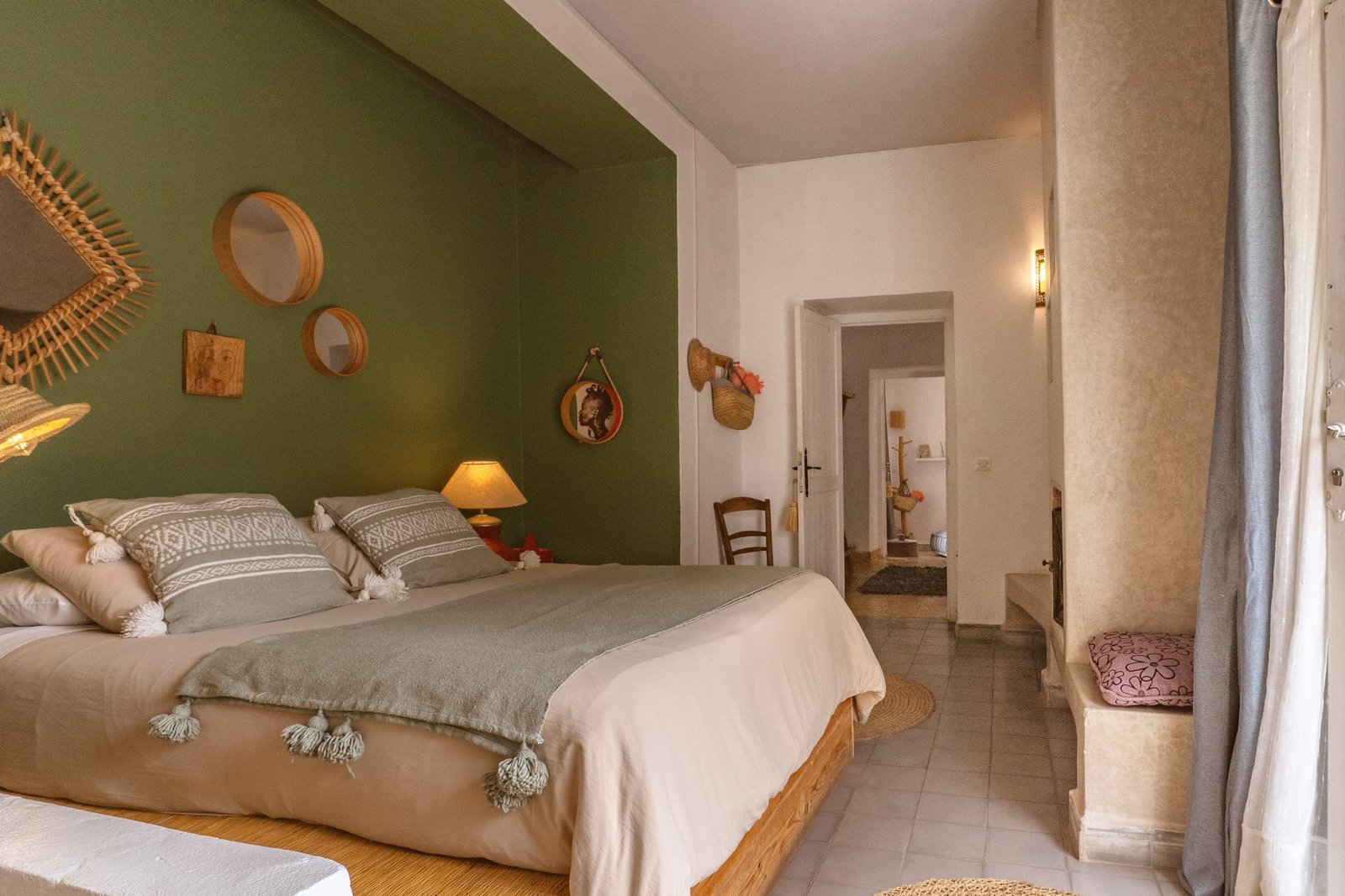 Le lit de la suite Bambou devant le mur vert, la porte ouverte sur la chambre voisine