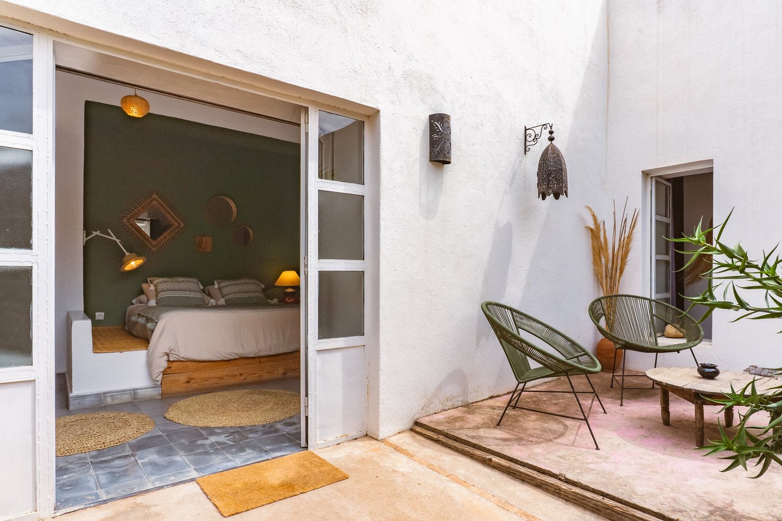 Le patio de la suite Bambou vu depuis la chambre, fauteuils verts et tapis de paille