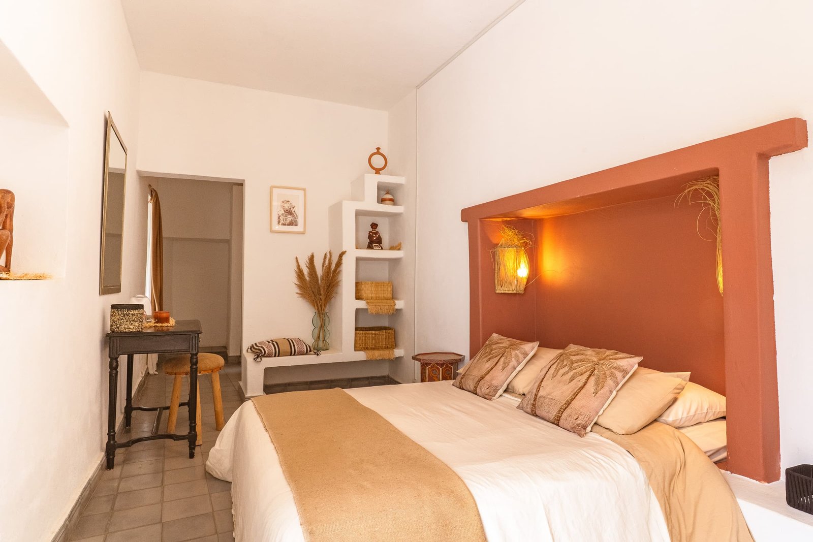 Le lit de la chambre Terracotta dans son alcôve de tadelakt, étagères et herbes séchées
