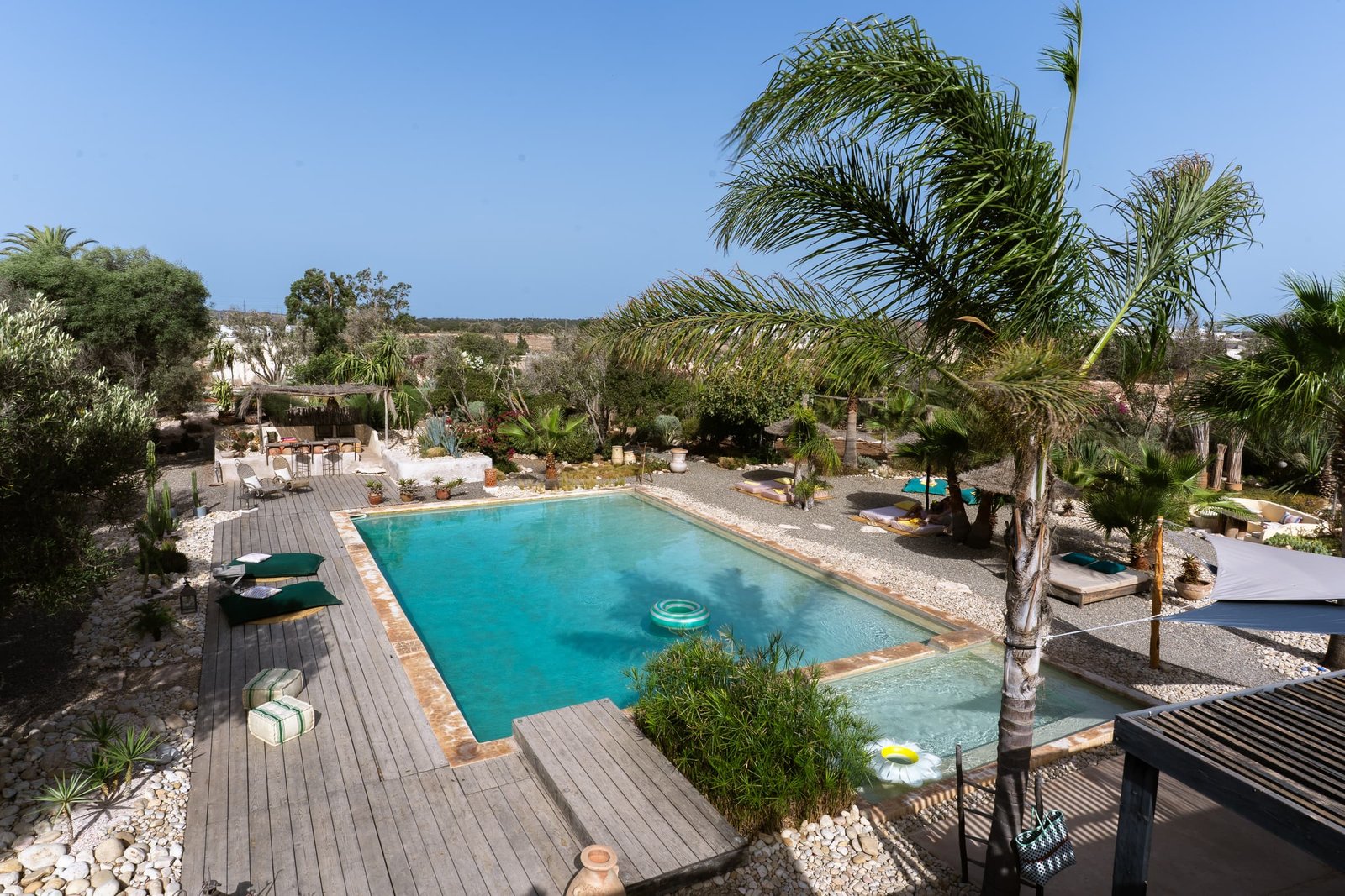 La piscine vue d’en haut, la terrasse en bois et les palmiers