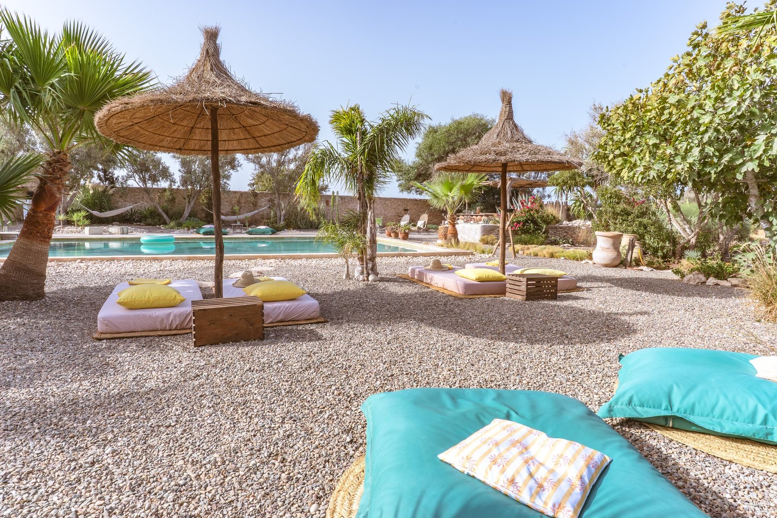 Les bains de soleil sous les parasols de paille, la piscine derrière