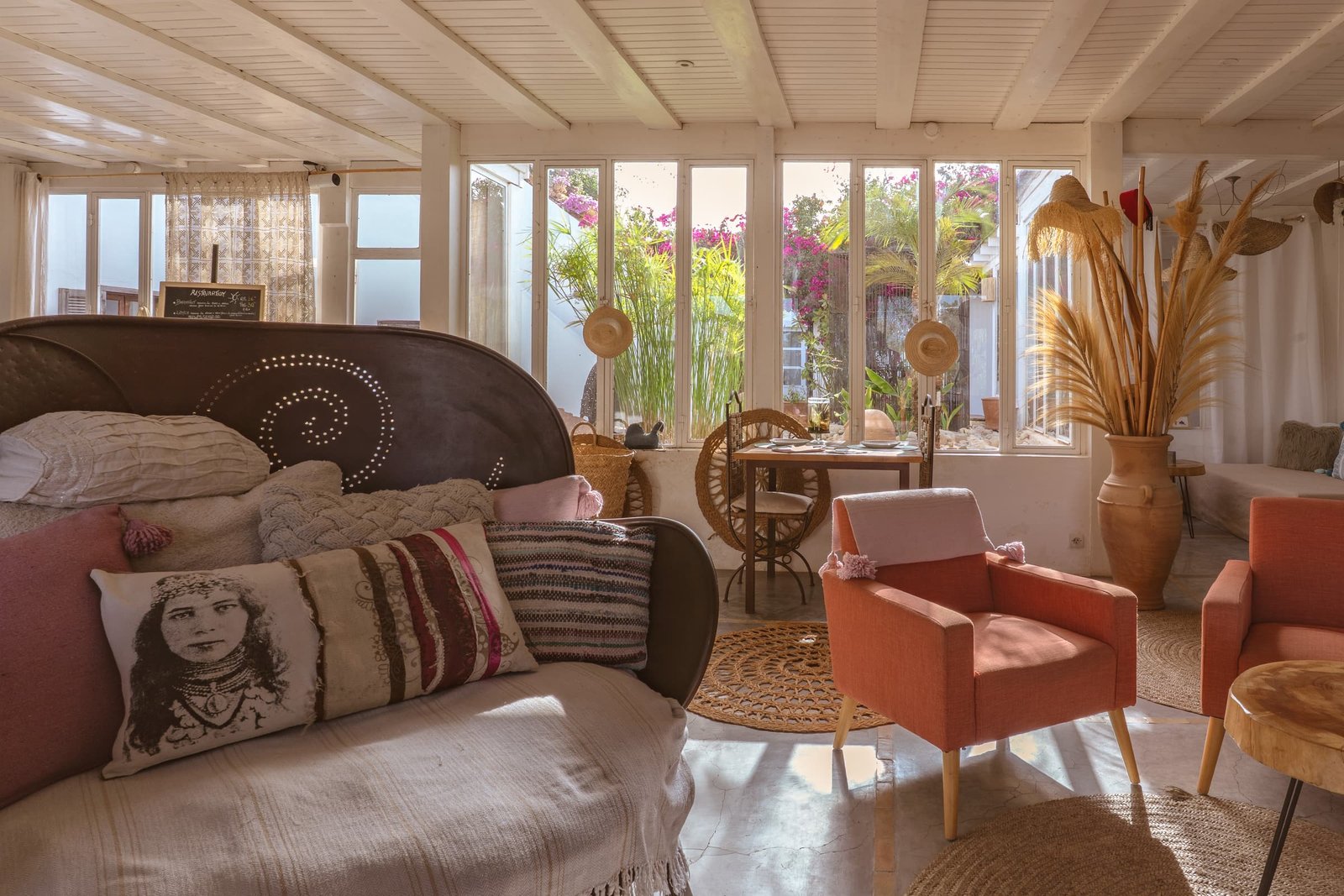 Le salon ouvert sur le jardin, banquette, coussins brodés et fauteuils corail