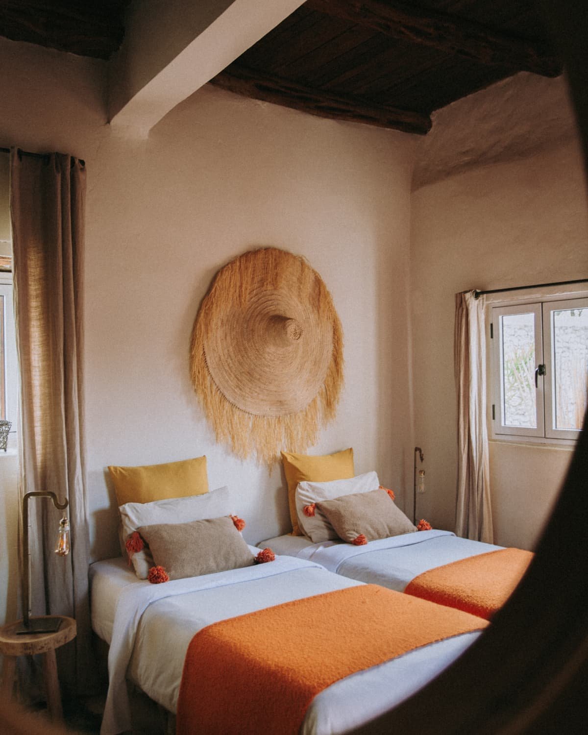 La chambre Bohème, jetés orange et coussins jaunes, chapeau de paille au mur