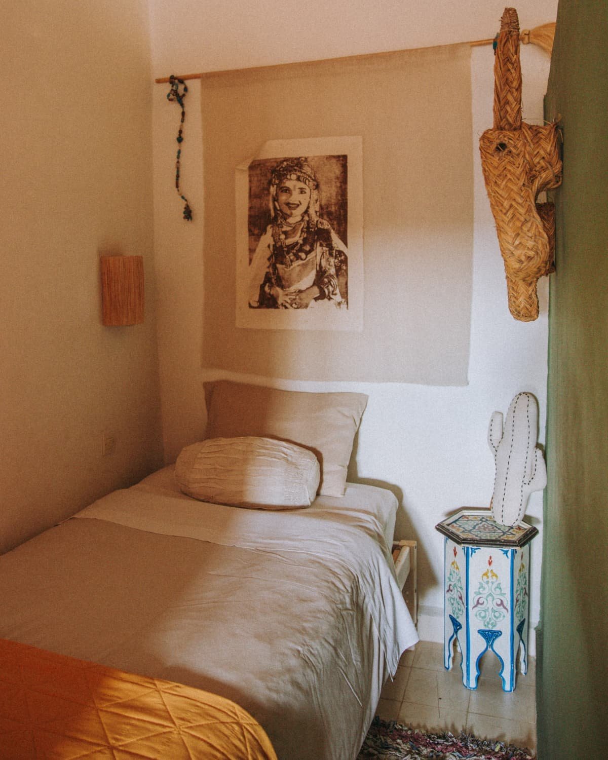 Le lit en alcôve de la chambre Bohème, tapis boucherouite et masque au mur