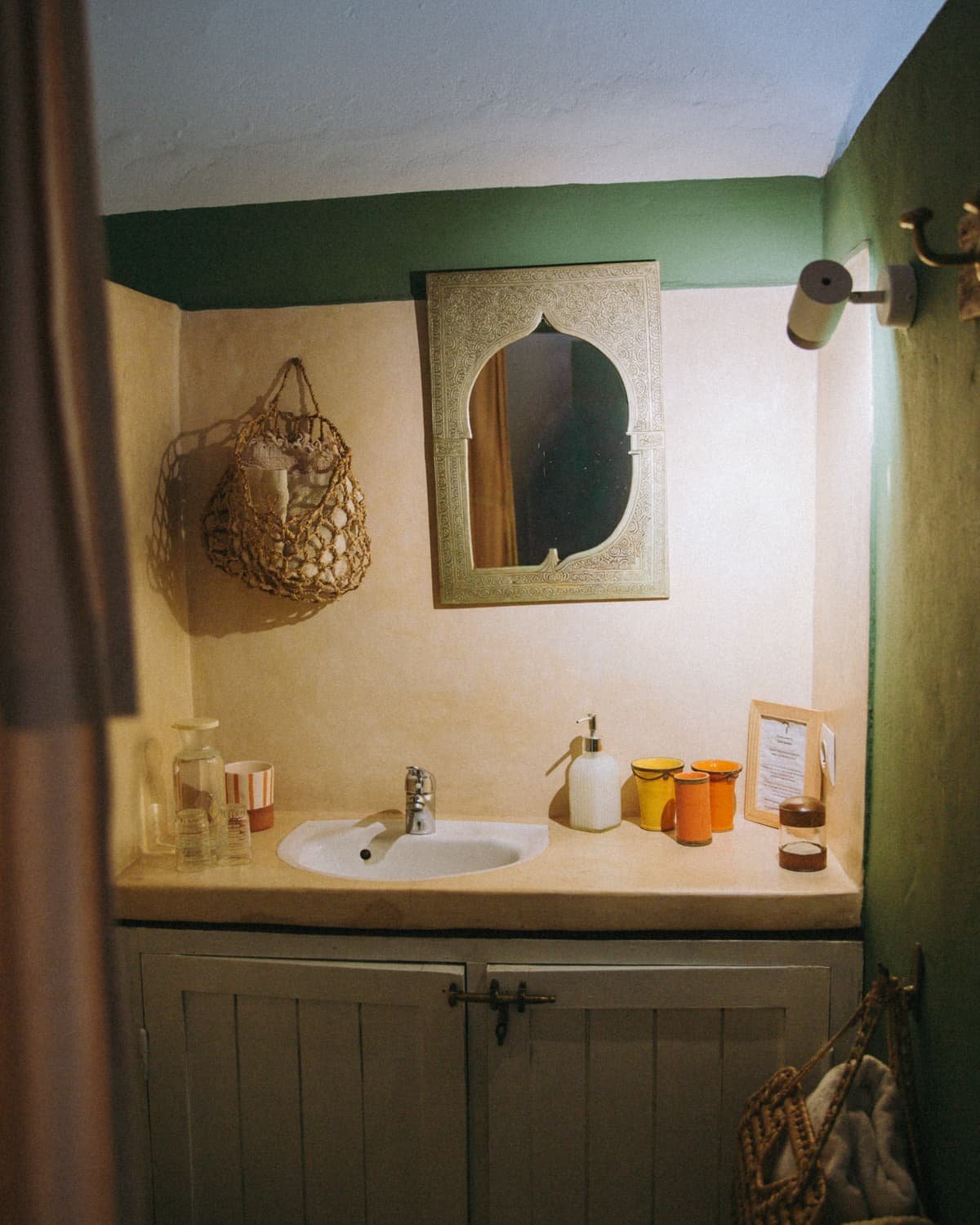 La salle de bain de la chambre Bohème, mur vert et vasque sous un miroir ancien