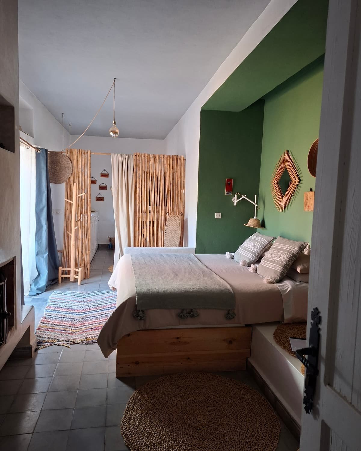 Le lit de la Suite Bambou devant le mur vert, sol en terre cuite