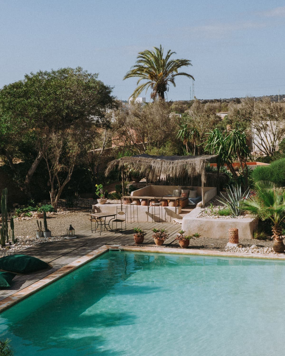 La piscine turquoise, un palmier et un hamac au fond du jardin