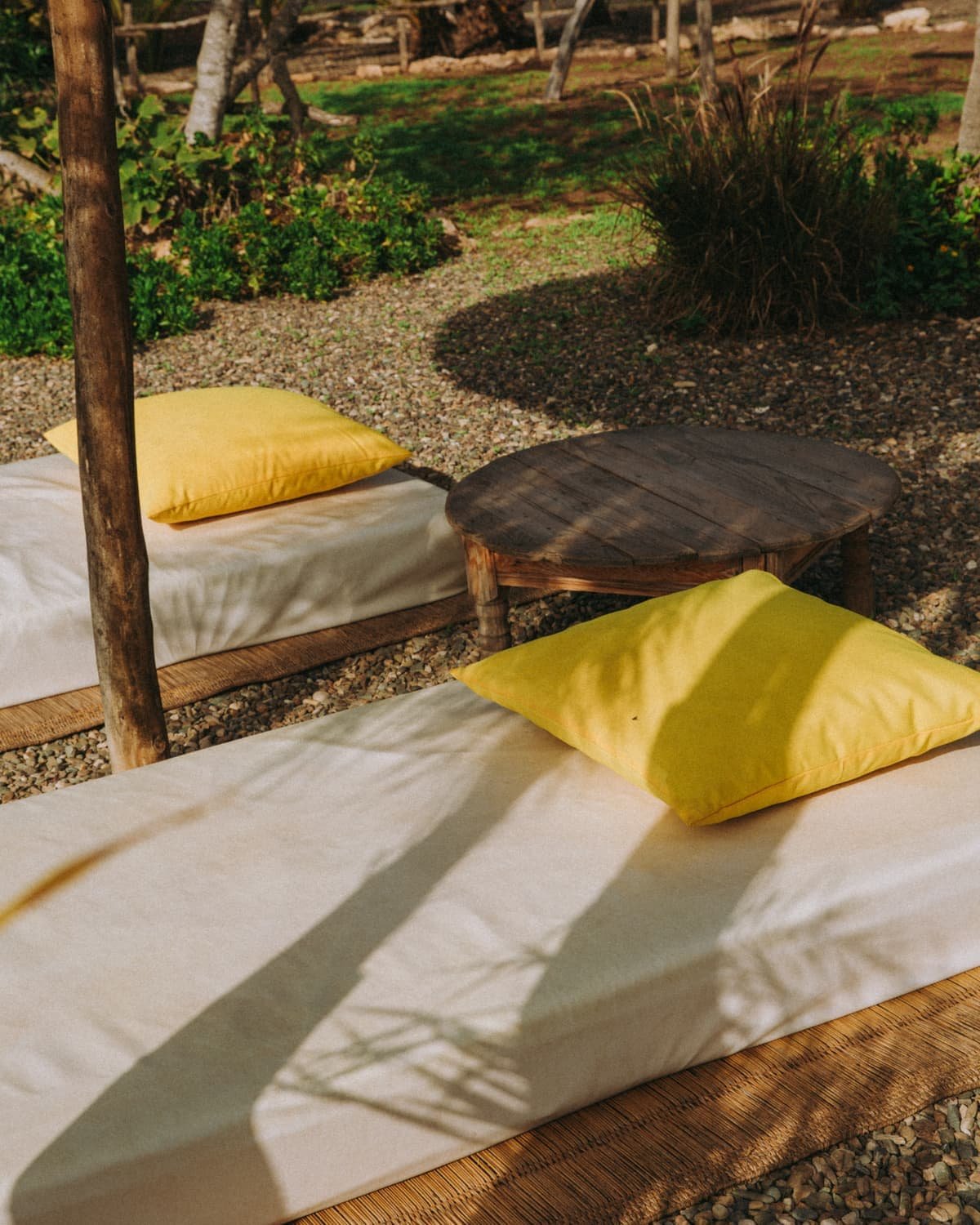 Lit de repos et coussins jaunes autour d’une table basse ronde