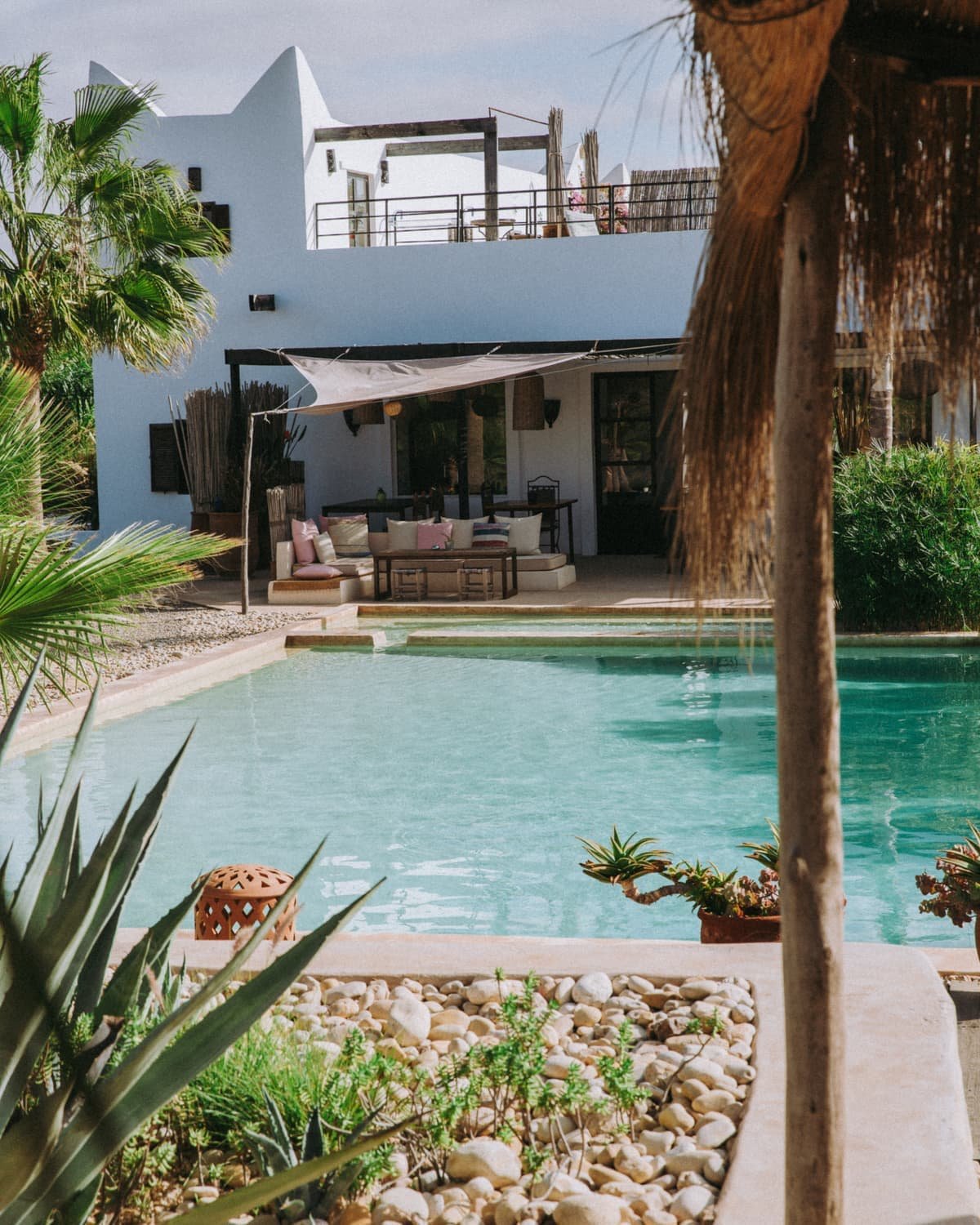 La maison vue depuis la piscine, sa terrasse couverte et son salon