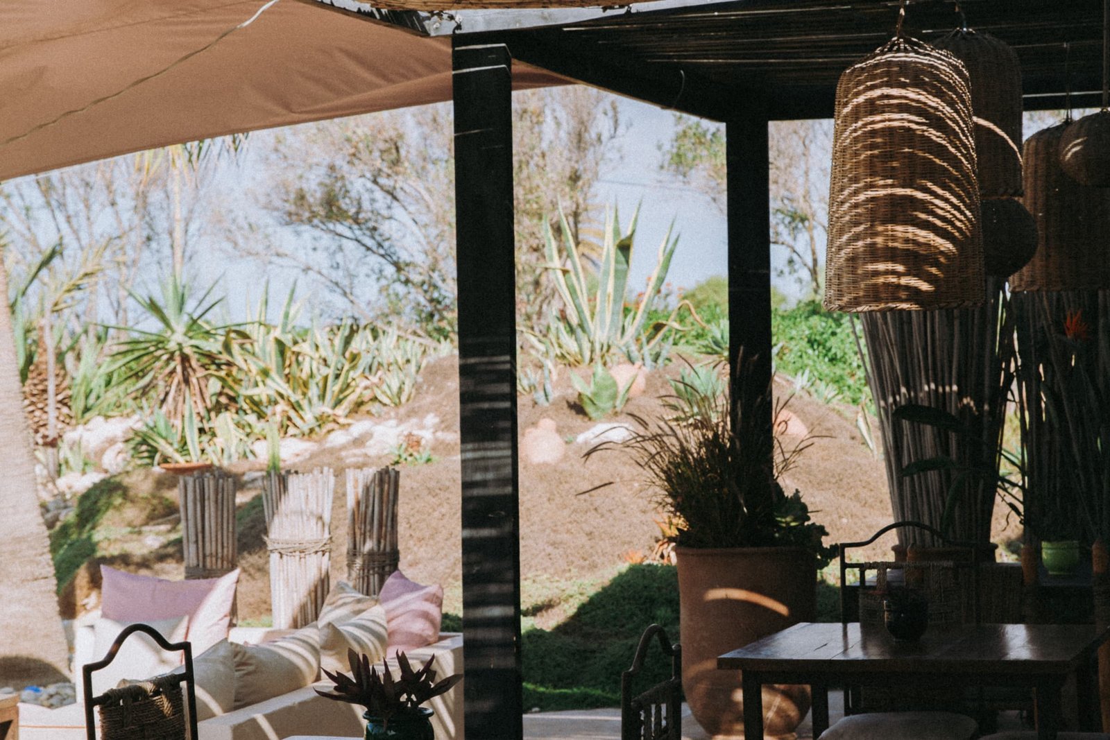 Salon d’exterieur sous une pergola en bois, table basse et fauteuils