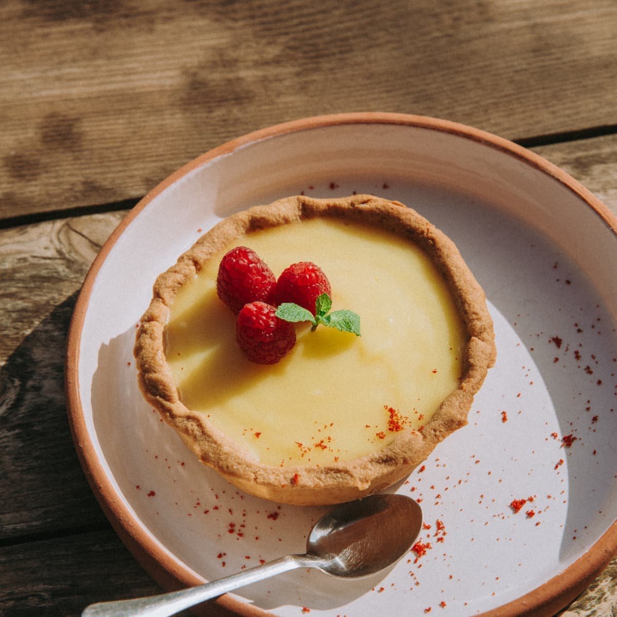 Une tarte au citron et ses framboises, dans un bol en terre cuite
