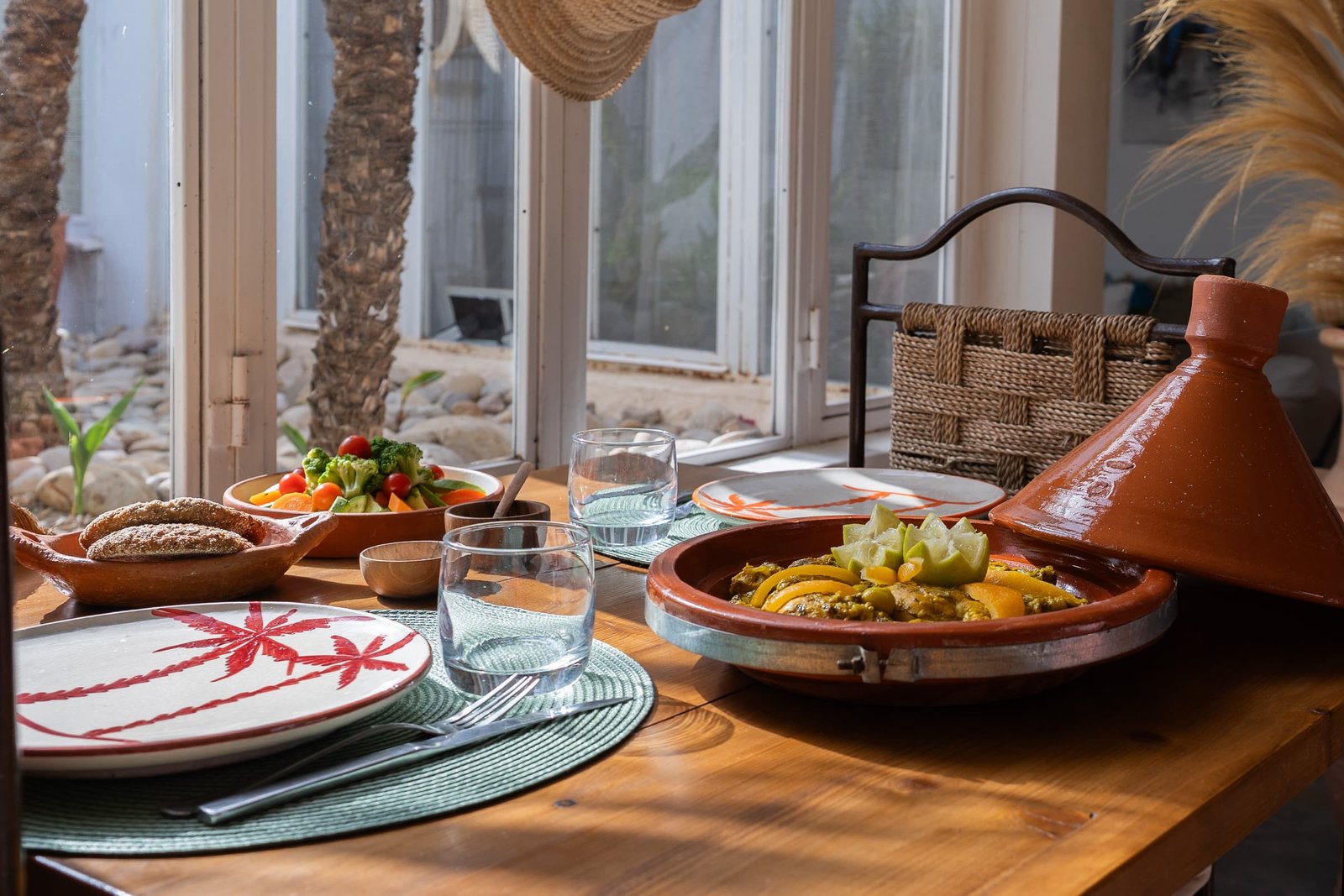 The evening tagine open on the laid table, plates and glasses facing the garden